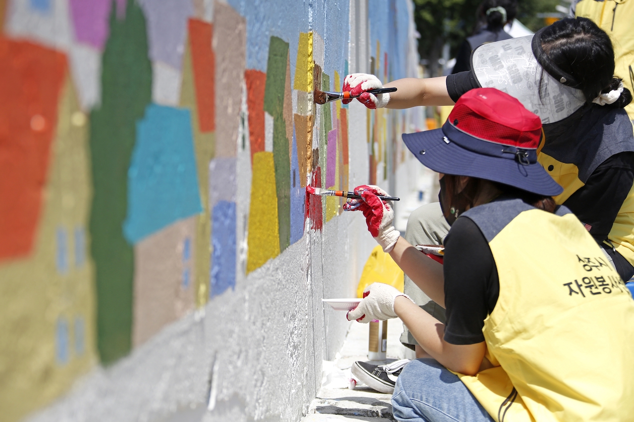 Sinbong-dong, Sangju-si, Gyeongsangbuk-do, South Korea - September 12, 2021: Volunteers are drawing mural on the wall of a house with brush