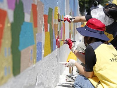 Sinbong-dong, Sangju-si, Gyeongsangbuk-do, South Korea - September 12, 2021: Volunteers are drawing mural on the wall of a house with brush